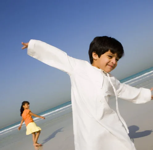 A boy on a beach with his arms out like wings.