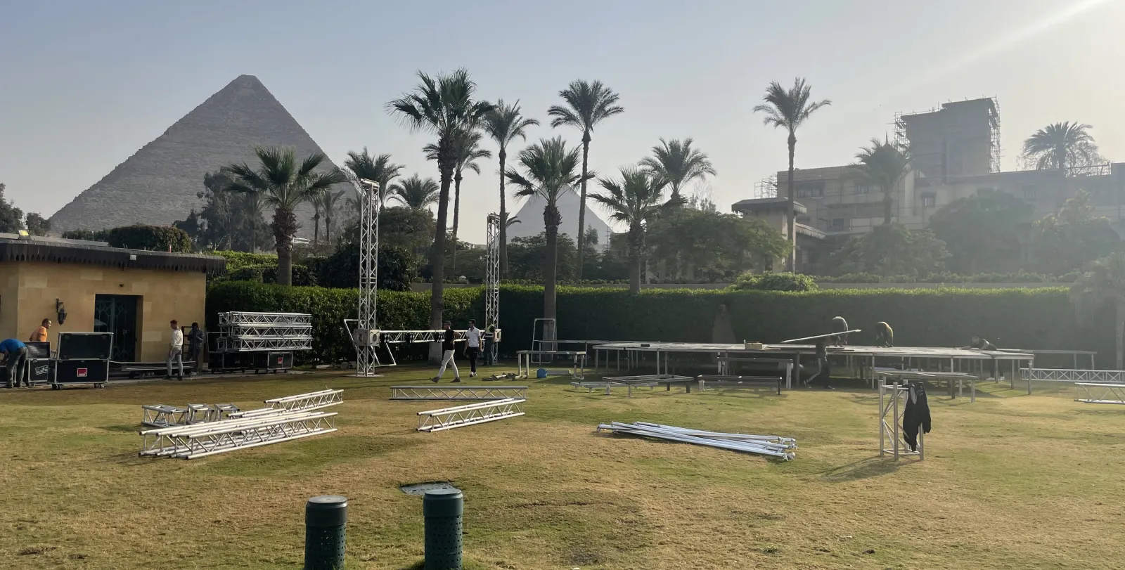 Truss towers standing on the lawn, flight cases, the pyramid behind.