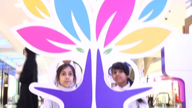 Two girls inside the board, their faces in its two holes, at RAK Mall