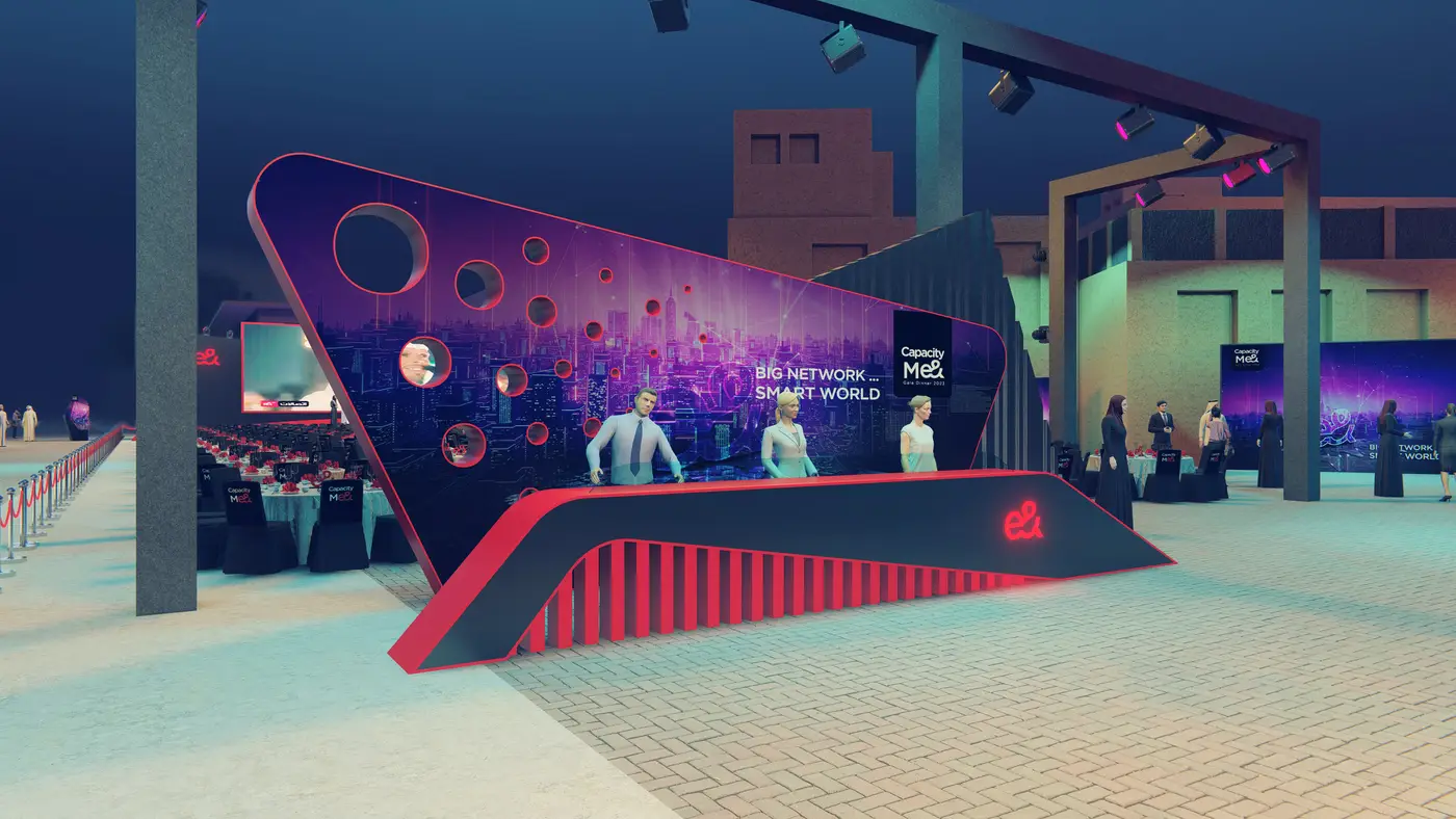 Proposal render, option A: a welcome desk under a sloping black and purple wall, Big network smart world, with the Capacity Me& logo and a red e&