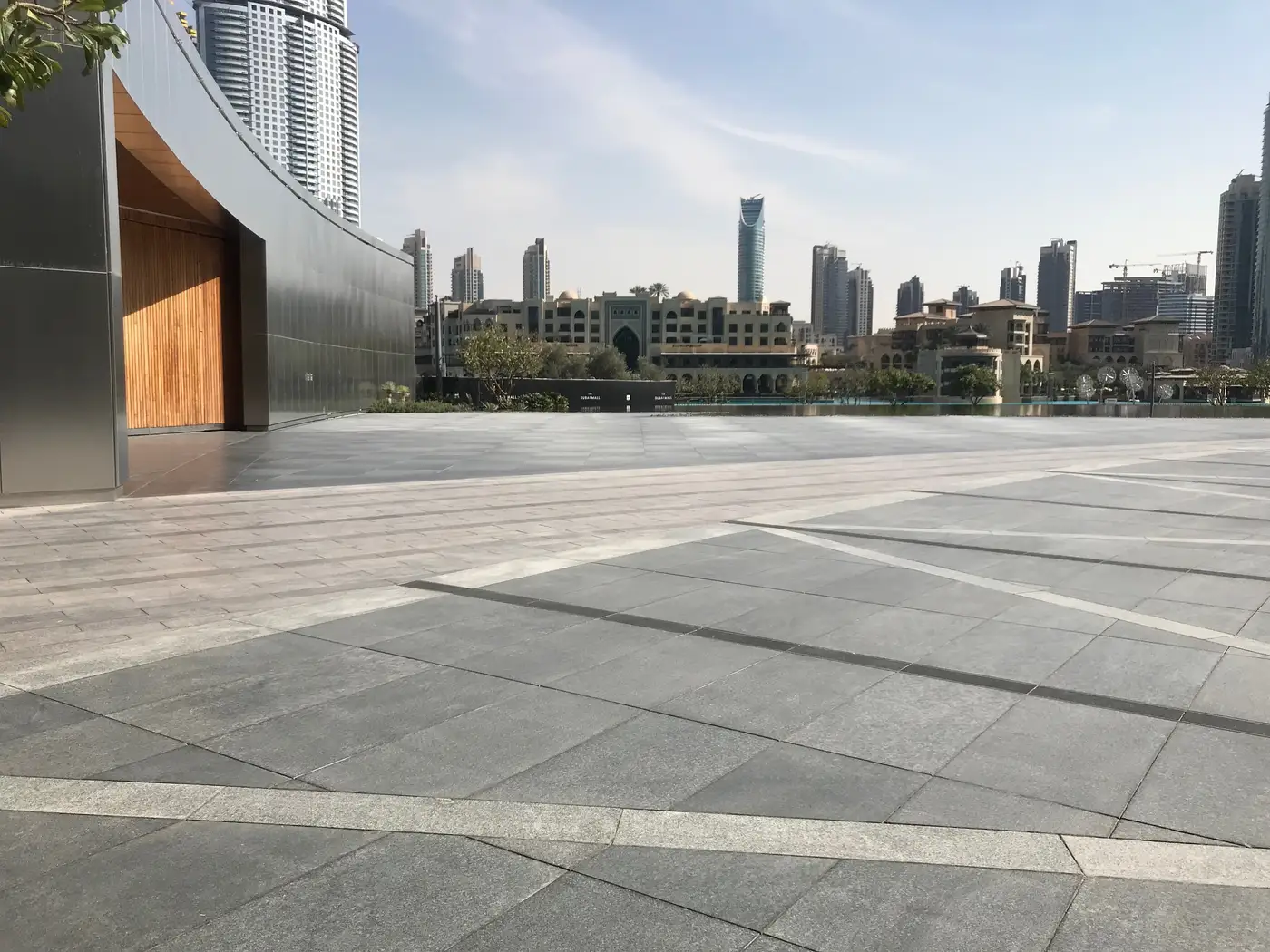 Photograph: the empty stone terrace of The Pavilion in daylight, the towers of Downtown Dubai beyond