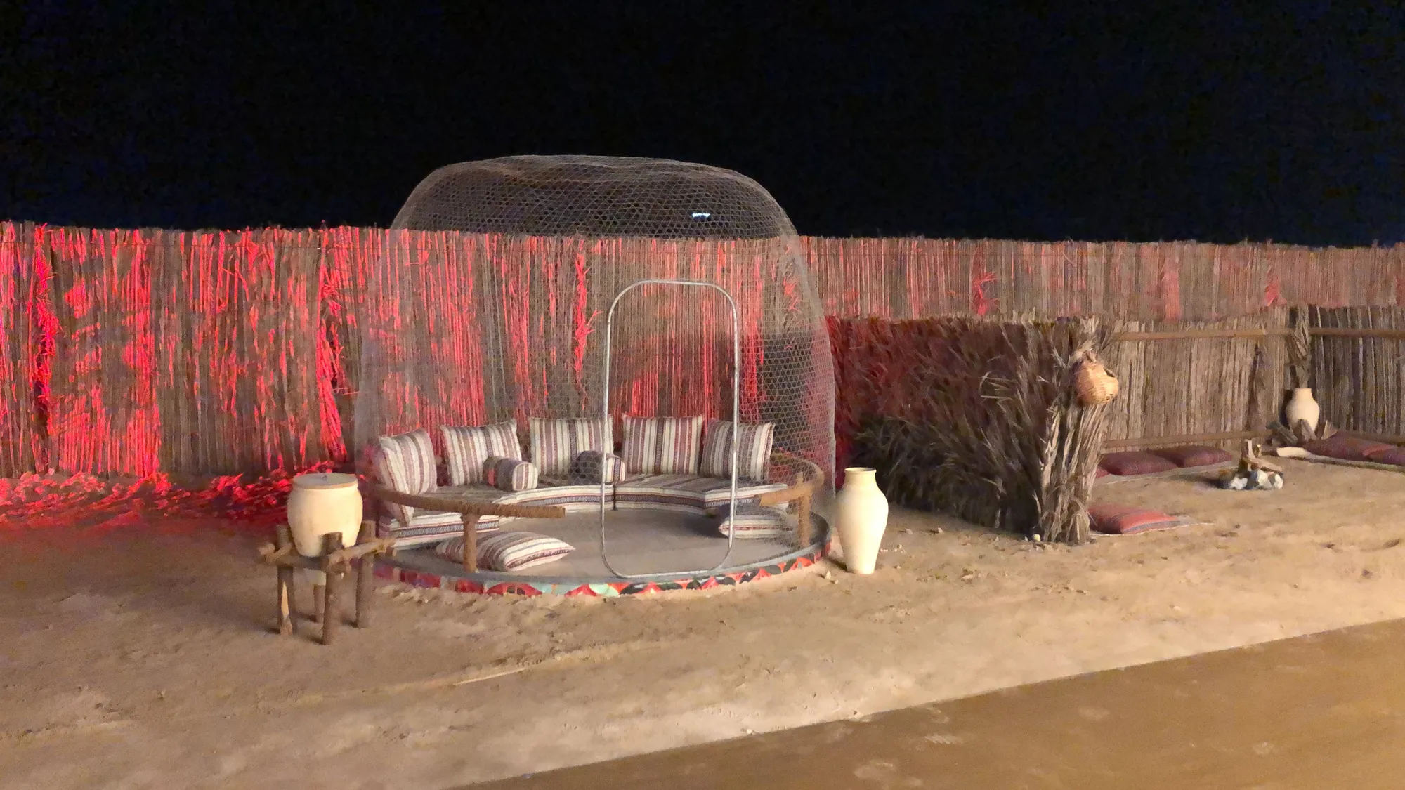 The glass-dome majlis, lit: a clear dome over cushions and carpets on the sand